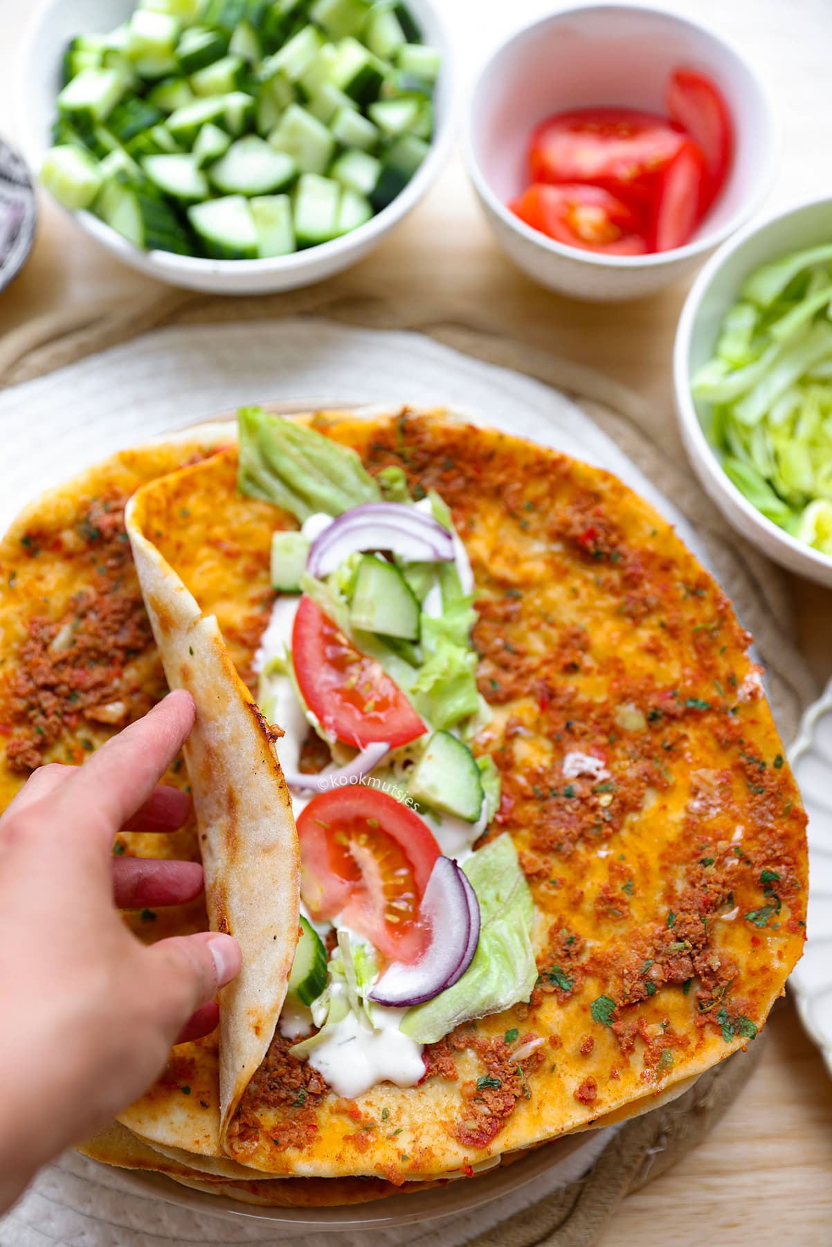 Opgerolde lahmacun gevuld met sla, tomaat en verse kruiden.