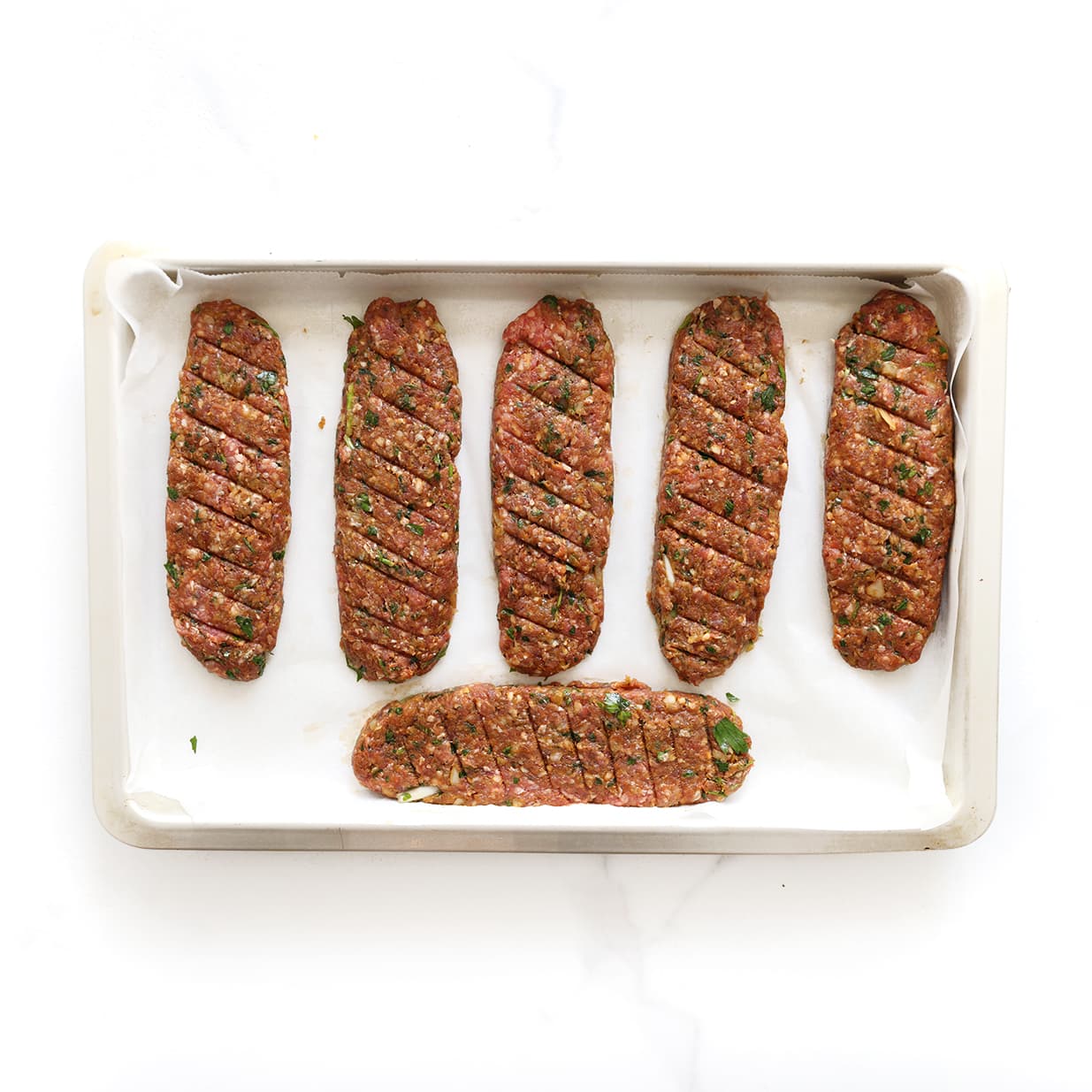 Langwerpige gehaktstaven voor Beyti kebab op bakplaat