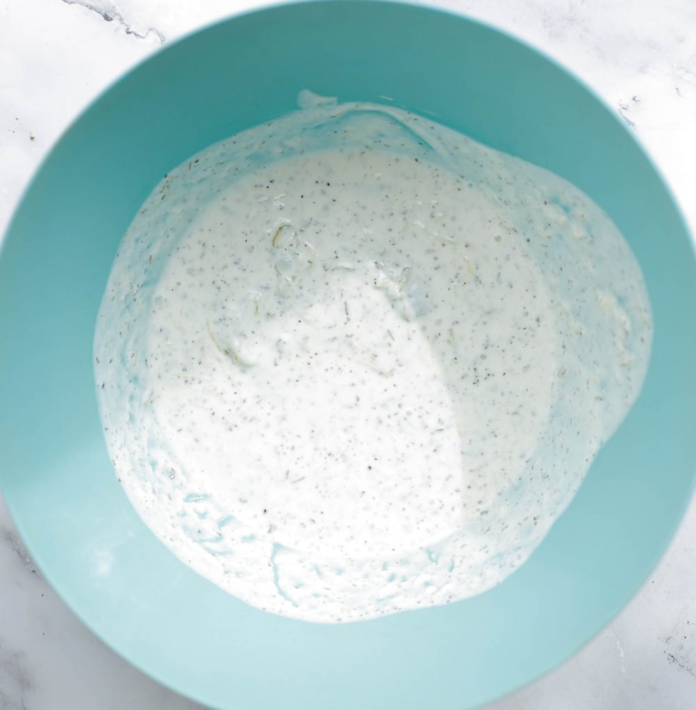 Rasp de augurk. Doe de yoghurt, knoflookpoeder, uienpoeder, geraspte augurk en droge basilicum in een kom. Meng goed. Voeg zout toe naar smaak.