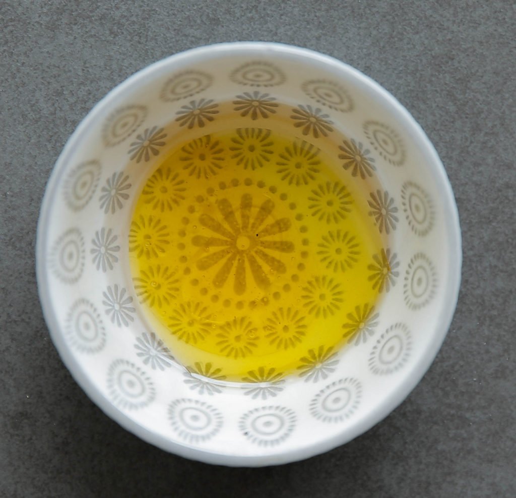 Doe de azijn samen met de olijfolie en honing in een diepe kom. Meng goed.