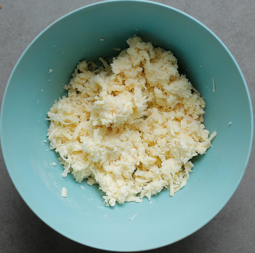 Doe de geraspte kaas samen met de parmezaanse kaas in een diepe kom. Meng goed.