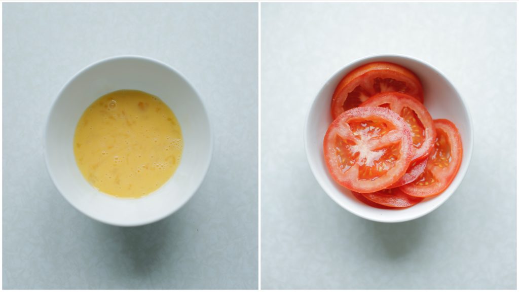 Breek de eieren boven een kom en kluts goed. Voeg zout toe naar smaak. Snijd één grote tomaat in plakken.