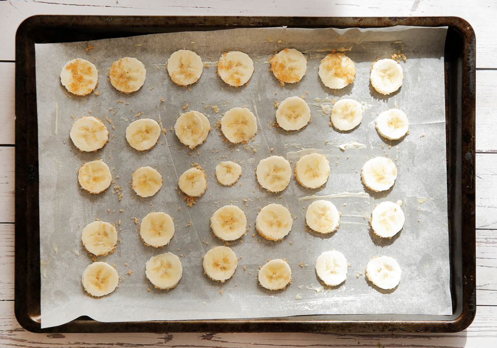 Verdeel de plakjes banaan over een bakplaat met bakpapier.