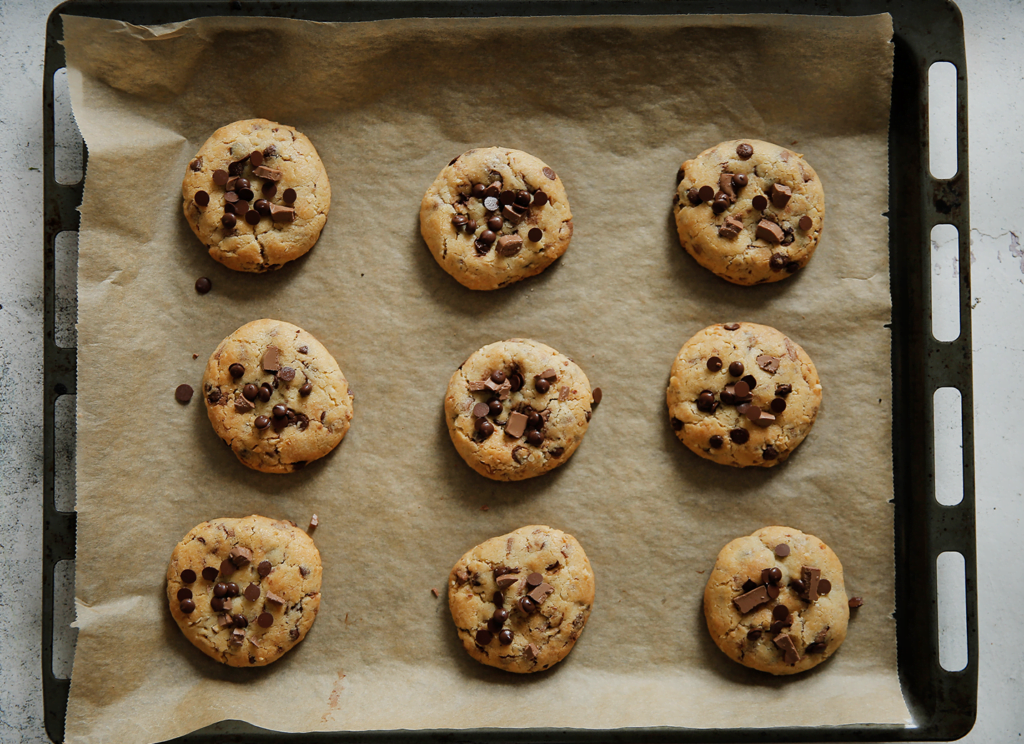 Zodra de koekjes uit de oven komen, druk er dan meteen wat chocoladedruppels op. Doe dit wanneer de koekjes nog warm zijn, zodat het goed plakt.