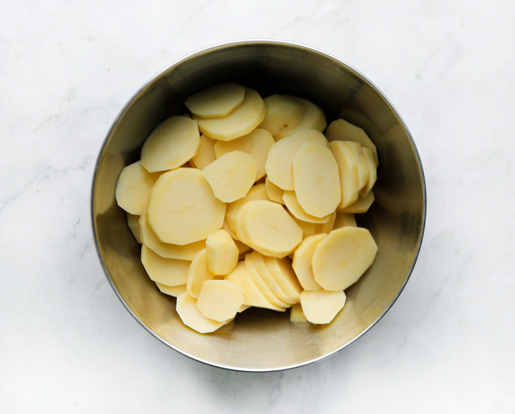 Schil en snijd de aardappels in schijfjes.