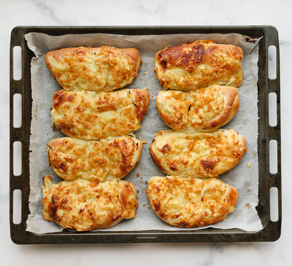 Zet de kaas-uienbroodjes in een voorverwarmde oven op 200 ℃. Bak 12-15 minuten of tot de broodjes mooi goudbruin zijn gekleurd. Dek de broodjes direct af met een theedoek zodra ze uit de oven komen.