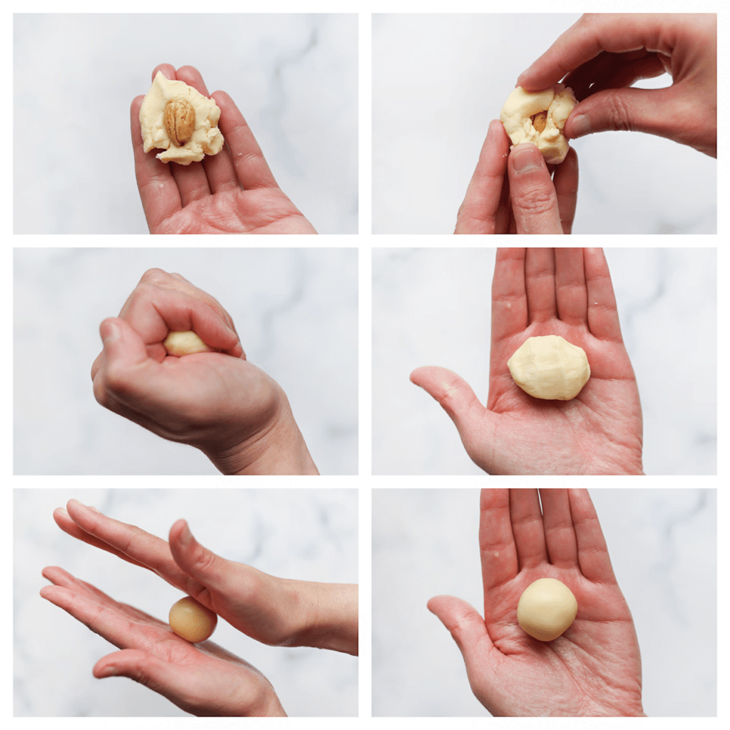 Neem wat van het koekjesdeeg (15 g). Vul dit met een gebakken amandel, knijp/druk goed dicht en rol dan met je handpalmen tot een bol. Herhaal de werkwijze.