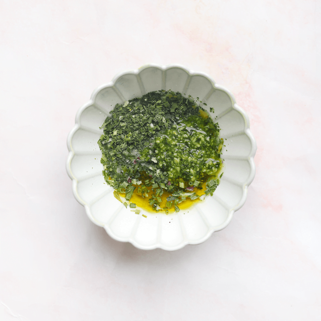 Doe de groene pesto, olijfolie, het citroensap en de Italiaanse kruiden in een kom. Meng alles goed samen tot een geheel.