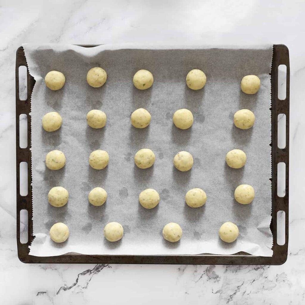 Plaats de ma&iuml;zena-pistachekoekjes op een bakplaat bekleed met bakpapier.