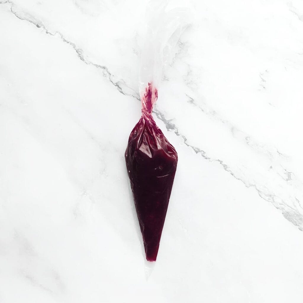 Giet de bosbessensiroop vervolgens in een spuitzak. Leg apart.