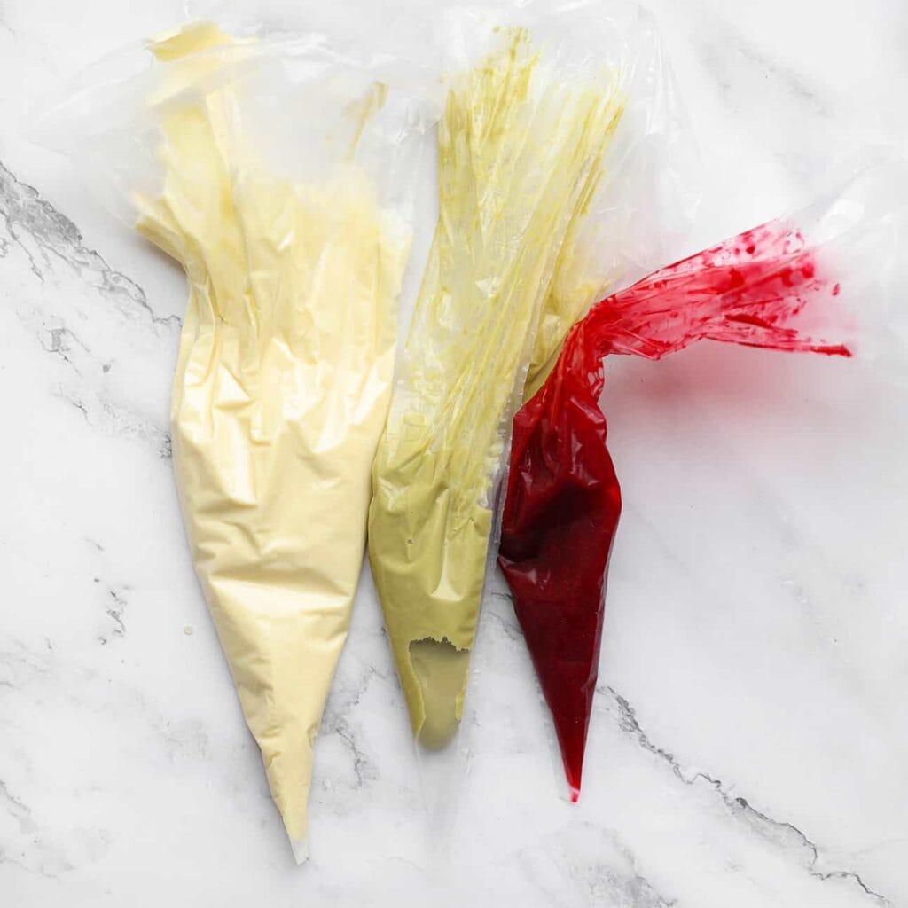 Doe de witte chocolade, pistachepasta en frambozenjam in een spuitzak.