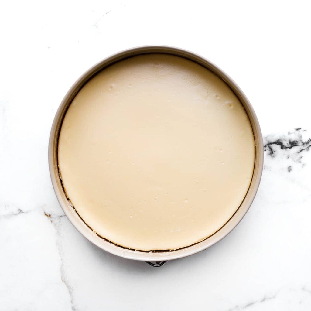 Zet de cheesecake in een voorverwarmde oven op 125 ℃ en bak 60-65 minuten, of totdat de zijkanten stevig zijn en het midden nog een beetje wiebelt. Schakel vervolgens de oven uit en laat de cheesecake nog 1 uur in de oven liggen. Dit helpt voorkomen dat de cheesecake inzakt of scheurt.