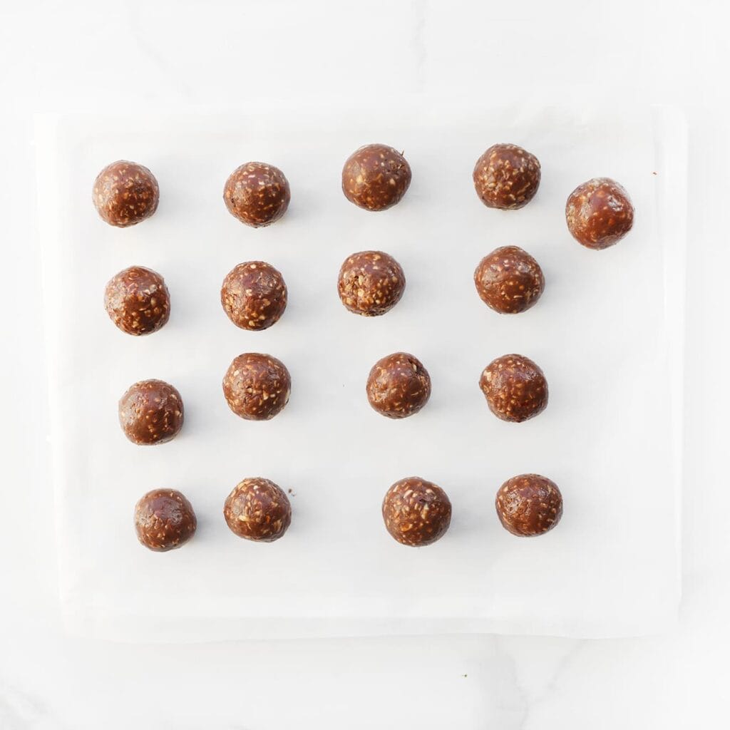 Leg de chocoladebollen op een vel bakpapier en zet ze 30 minuten in de vriezer om stevig te worden.