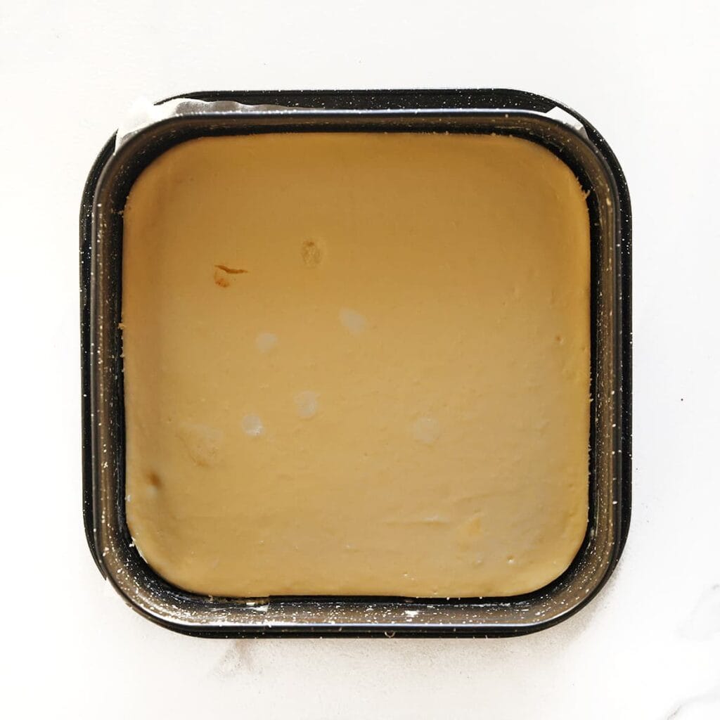 Zet de cheesecake in een voorverwarmde oven op 125 &deg;C. Bak 60&ndash;65 minuten, of tot de randen stevig zijn en het midden nog licht wiebelt. Zet de oven uit en laat de cheesecake 1 uur in de oven staan om scheuren te voorkomen. Laat de cheesecake vervolgens volledig afkoelen en zet hem daarna in de koelkast, bij voorkeur een hele nacht, zodat hij goed kan opstijven.