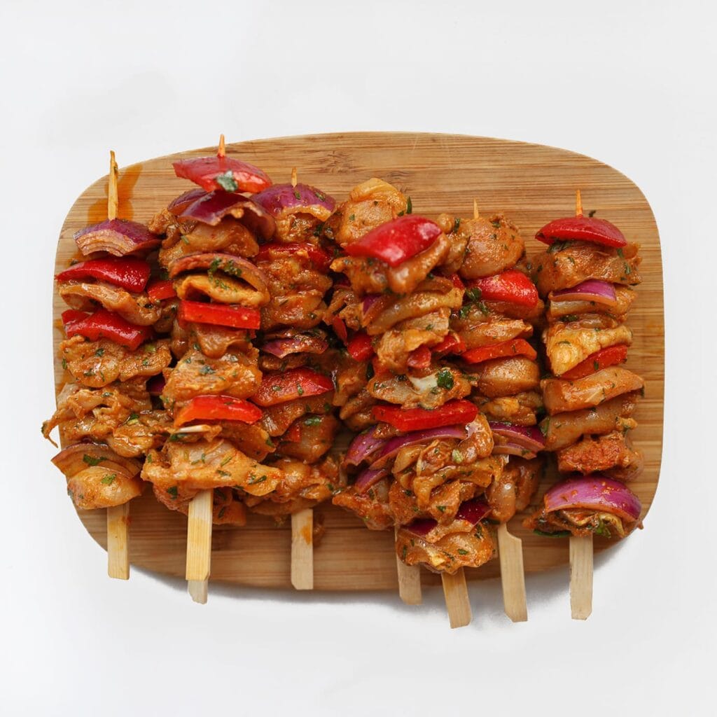 Rijg de kipblokjes afwisselend met paprika en rode ui aan de sat&eacute;prikkers. Rijg niet te strak.