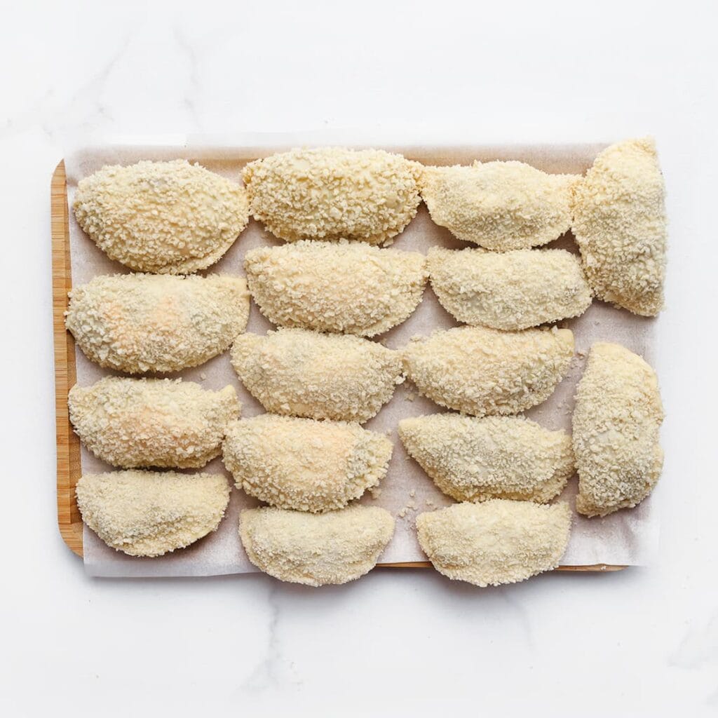 Leg de gevulde deegstukken op een vel bakpapier.