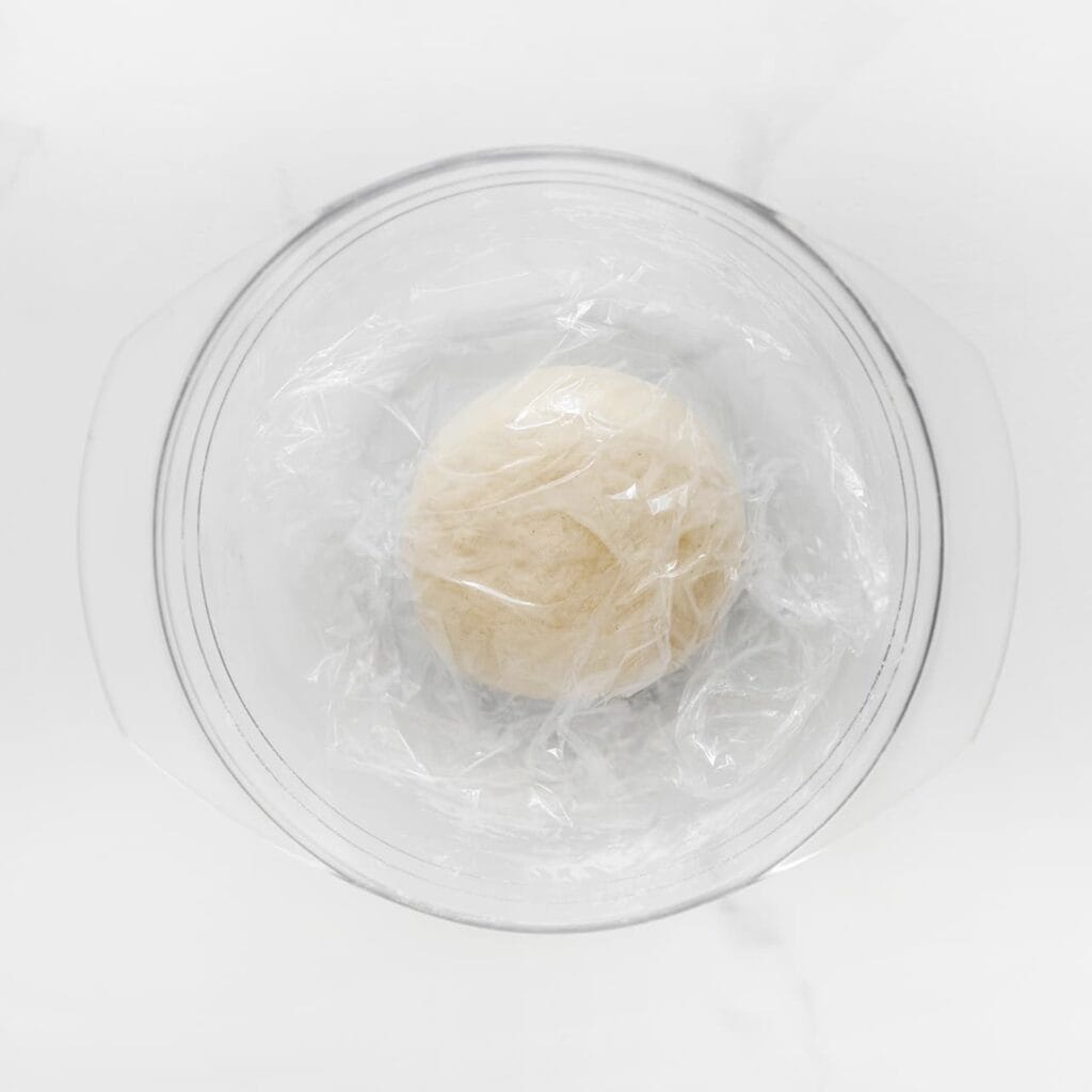 Dek het deeg af met huishoudfolie of een vochtige doek en laat het minimaal 30 minuten rusten. Heb je meer tijd? Laat het dan 1 uur rusten, zodat het deeg zachter wordt en makkelijker uit te rollen is.