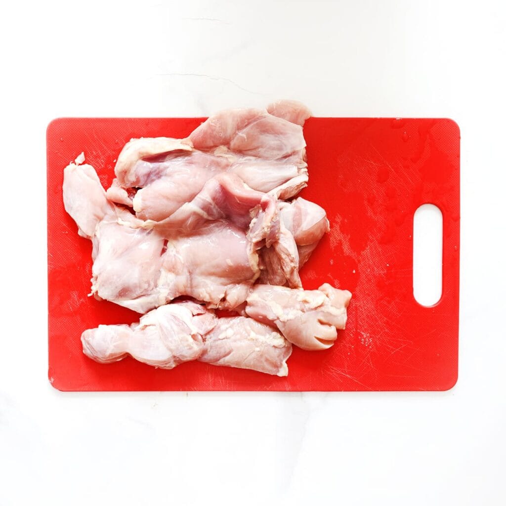 Was en snijd de kippendijen in stukken.