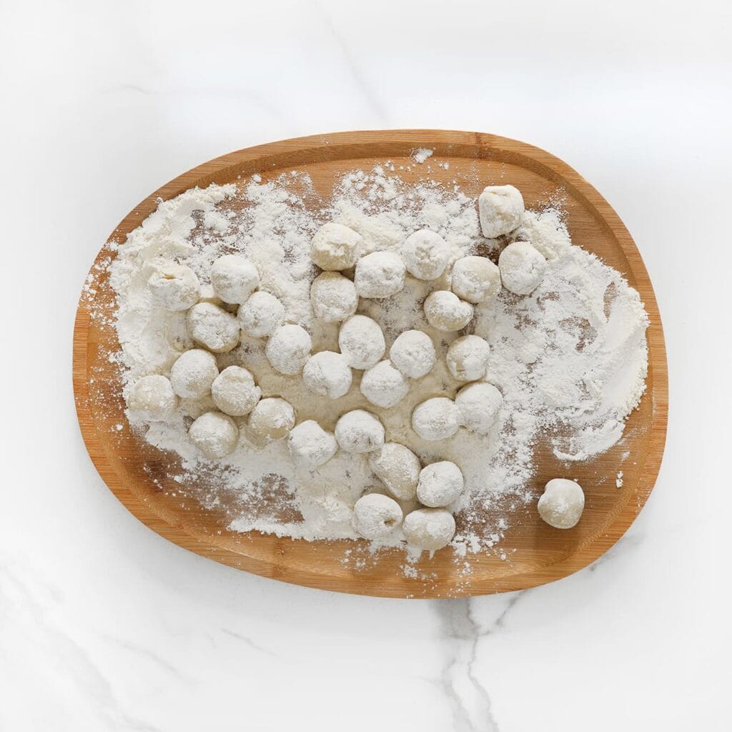 Wentel de deegbolletjes door de bloem.