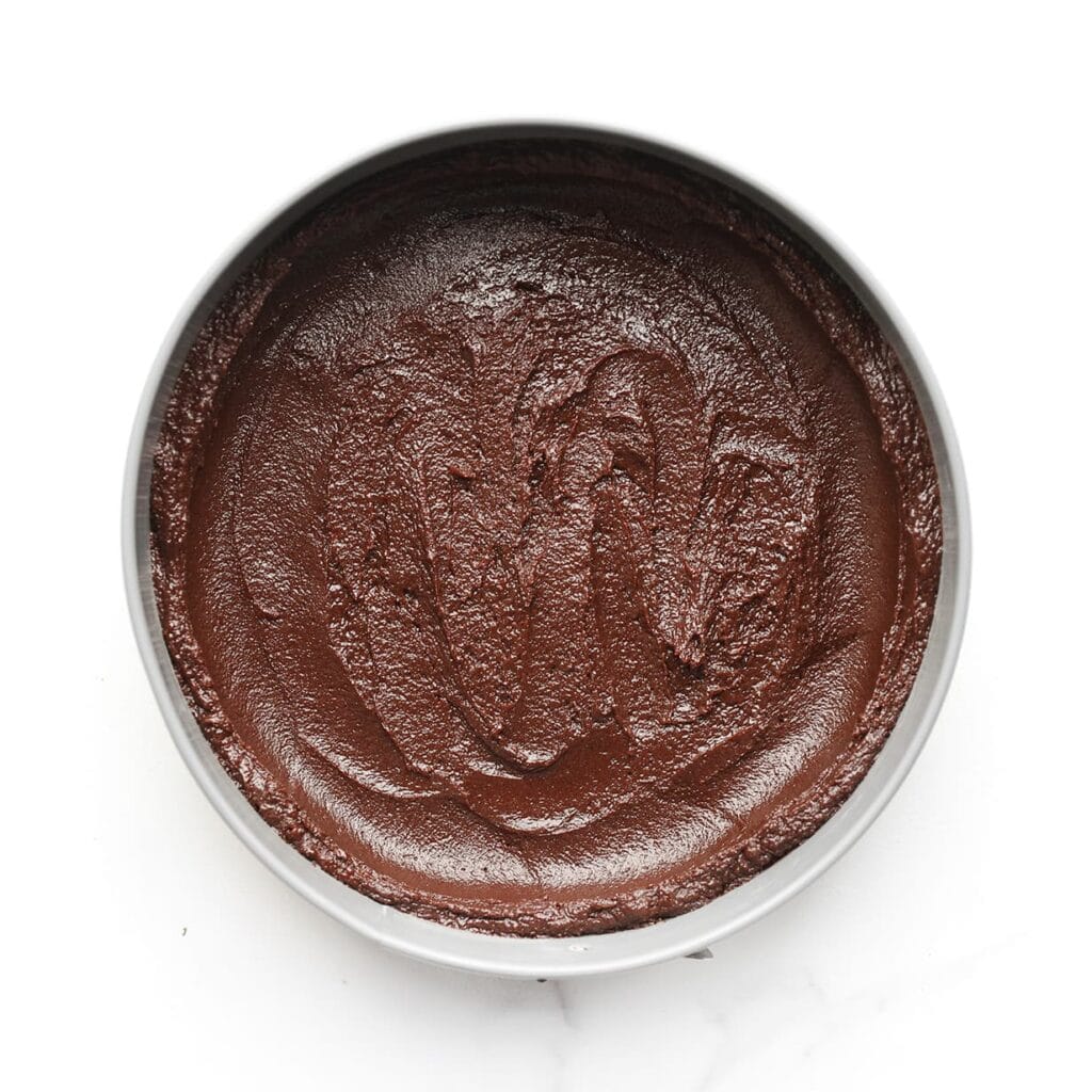 Verdeel het beslag over een ingevette en met bakpapier beklede bakvorm. Druk het beslag iets omhoog tegen de randen zodat er een lichte holte in het midden ontstaat.