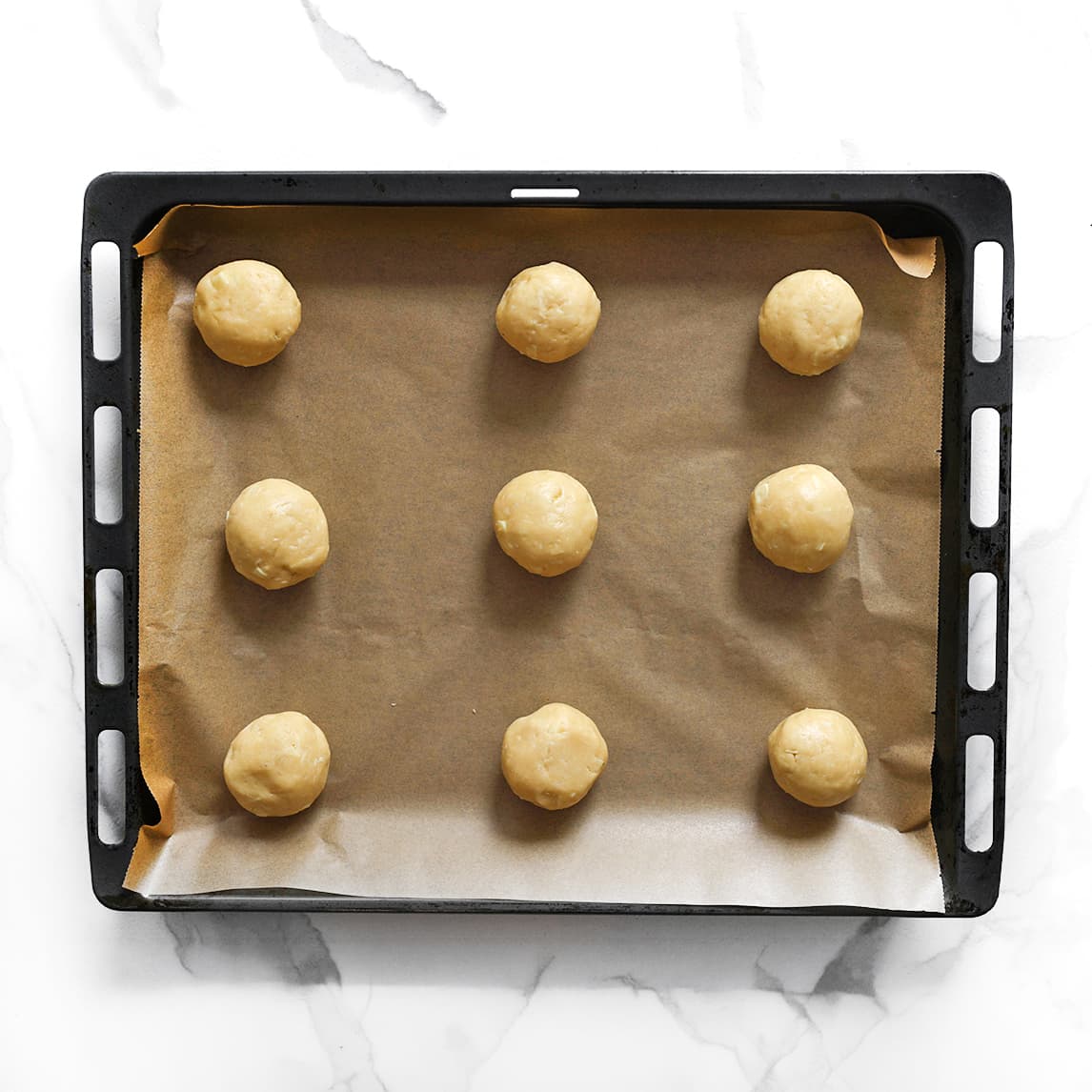 Koekjesdeeg op bakplaat met bakpapier leggen