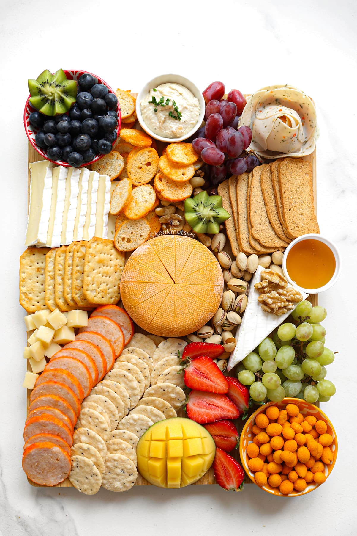 Close-up van een borrelplank met brie, druiven, kaasblokjes en noten