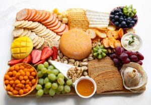Luxe borrelplank maken met kaas, druiven, fruit, noten en crackers op een houten plank