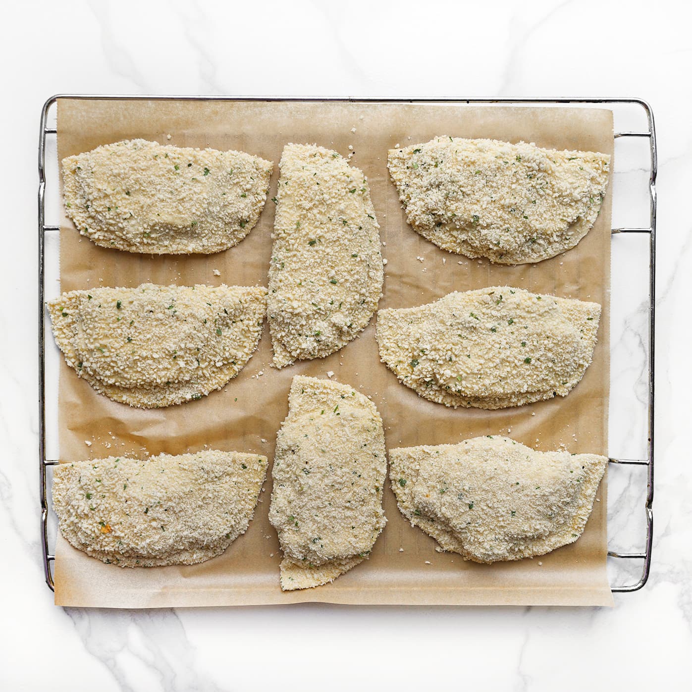 Gevulde en gecoate chicken caesar broodjes liggen op bakpapier.