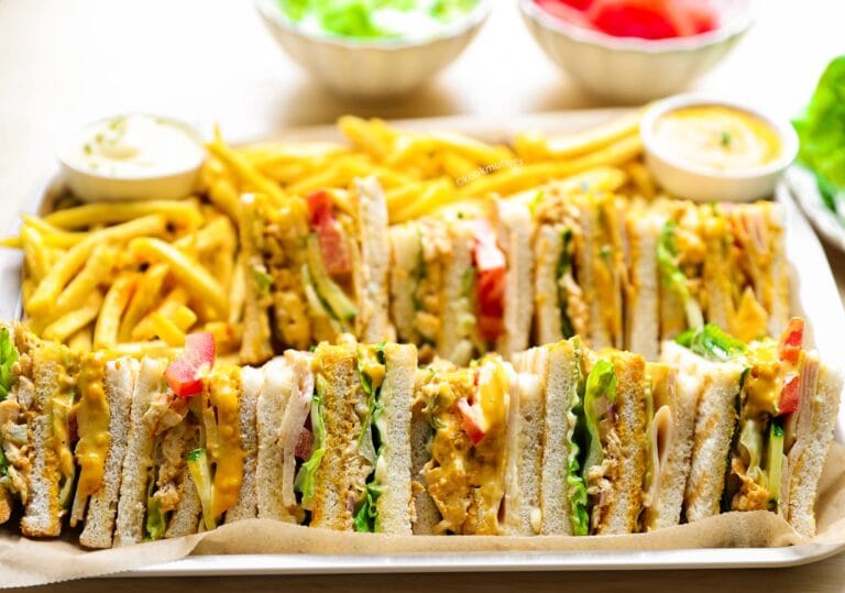 Club sandwich met kip, kipsalami, kaas, sla, tomaat, komkommer en romige mosterdsaus op geroosterd casinobrood