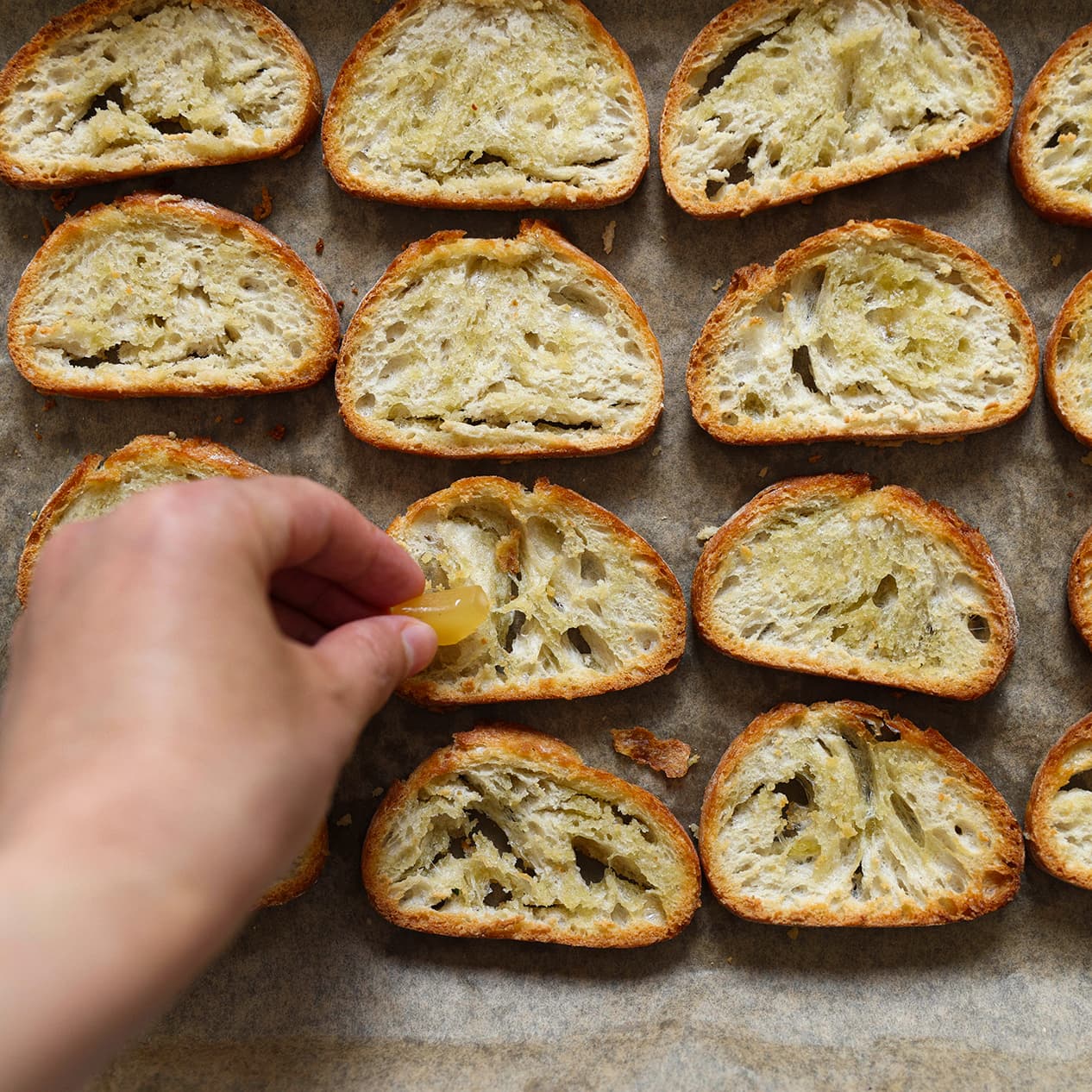 Knoflookteentje wordt over warm geroosterd brood gewreven