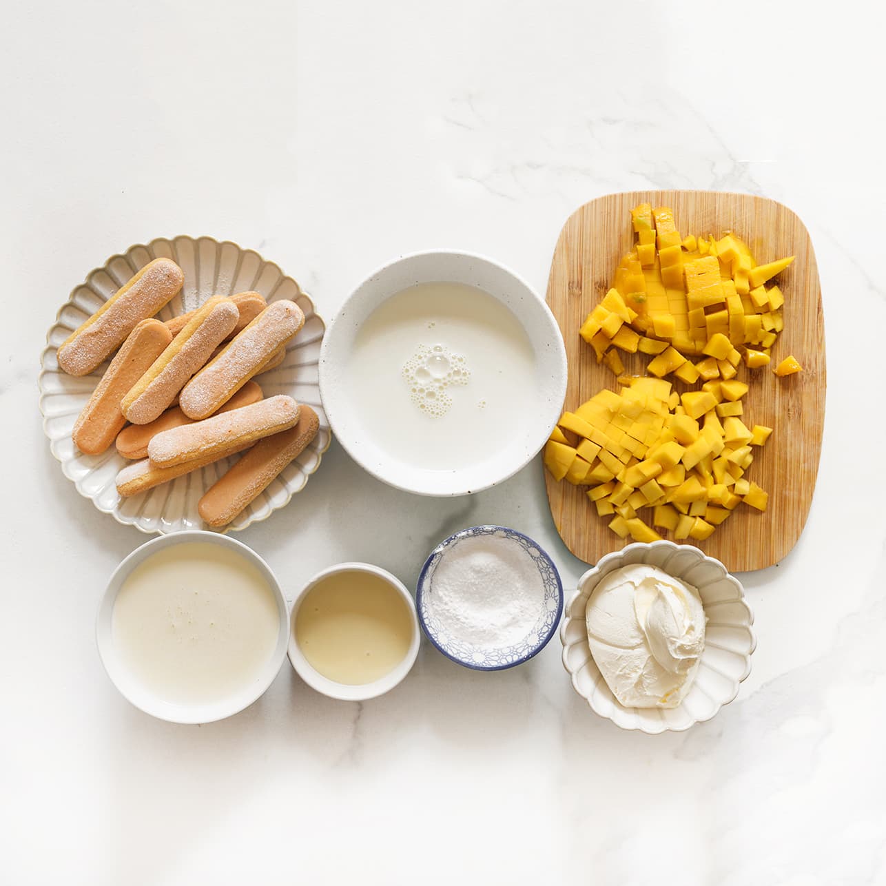 Mascarpone, poedersuiker, vanillesuiker, slagroom, mango en suiker klaar leggen voor het maken van mango tiramisu