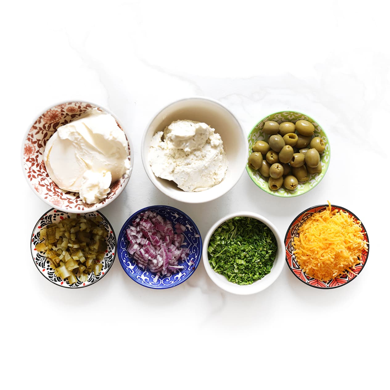 Ingrediënten voor een voetbal borrelplank met roomkaas, kruidenroomkaas, cheddar, augurken, olijven en borrelhapjes