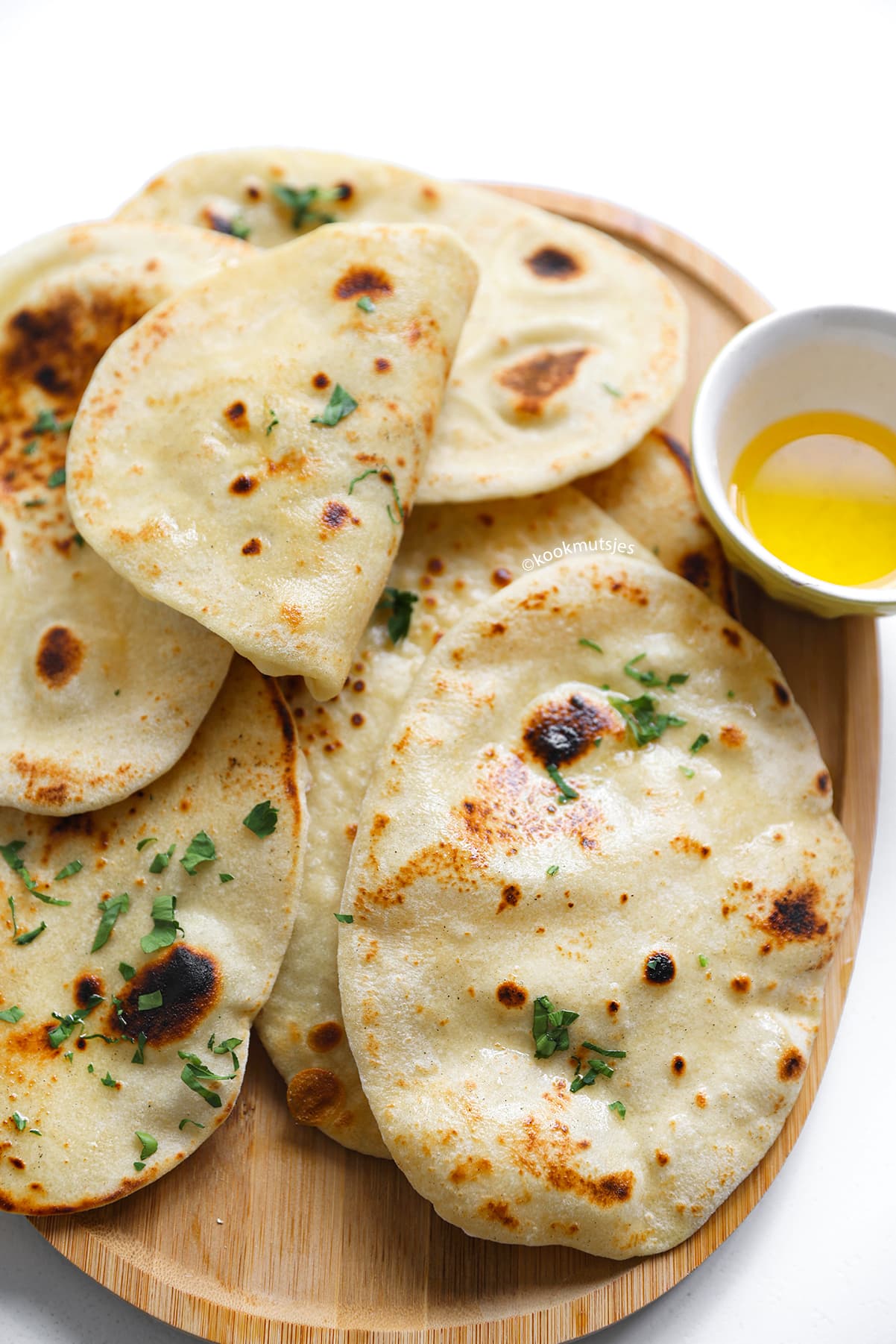 Stapel zelfgemaakte naan broodjes zonder gist met boter en verse peterselie