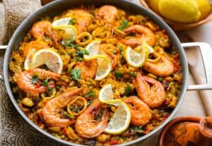 Paella met kip, garnalen en zeevruchten in een grote pan met saffraan en groenten