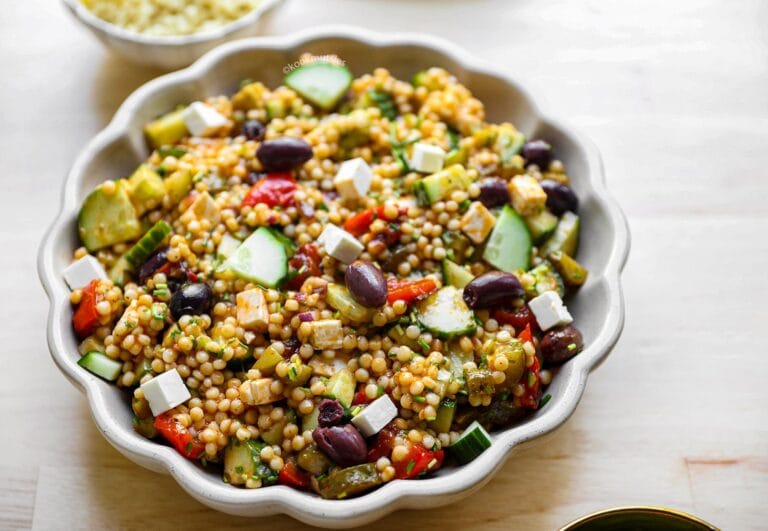 Frisse parelcouscoussalade met feta, avocado, komkommer, paprika, olijven en tomaten.