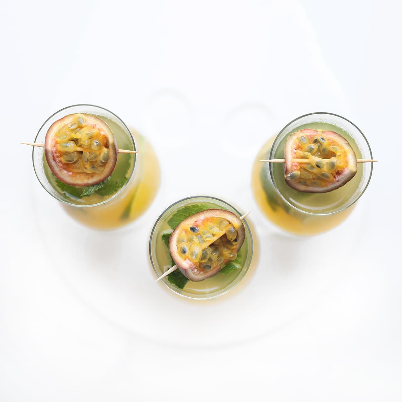 Passievrucht mojito mocktail gegarneerd met een halve passievrucht en verse munt.