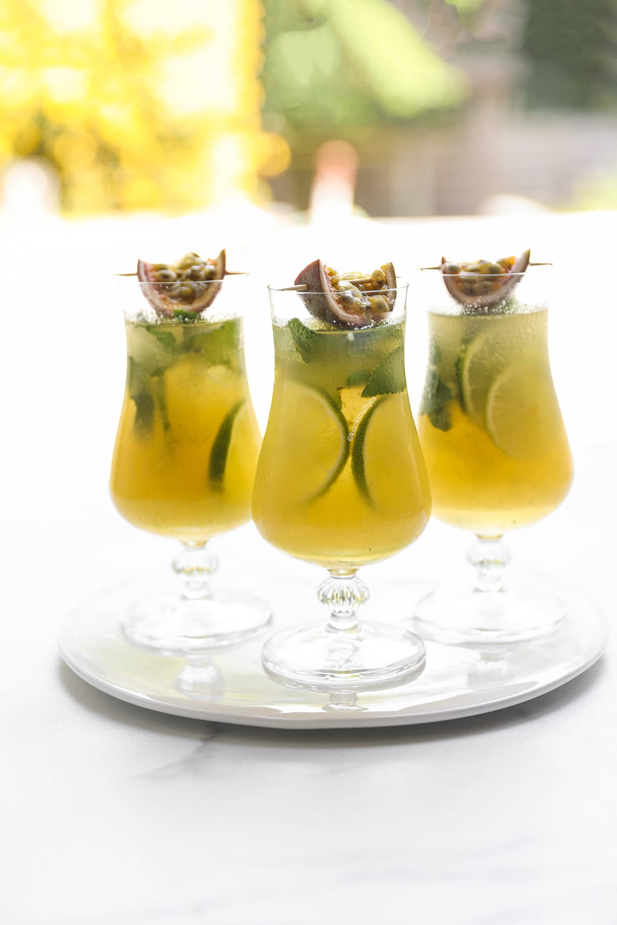 Alcoholvrije passievrucht mocktail met munt, limoen en ijsblokjes in een hoog glas.