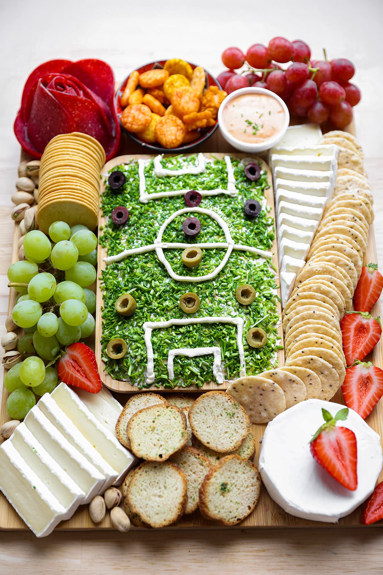 Volledige voetbal borrelplank met roomkaasveld, olijven, salami, kaas, druiven en toastjes