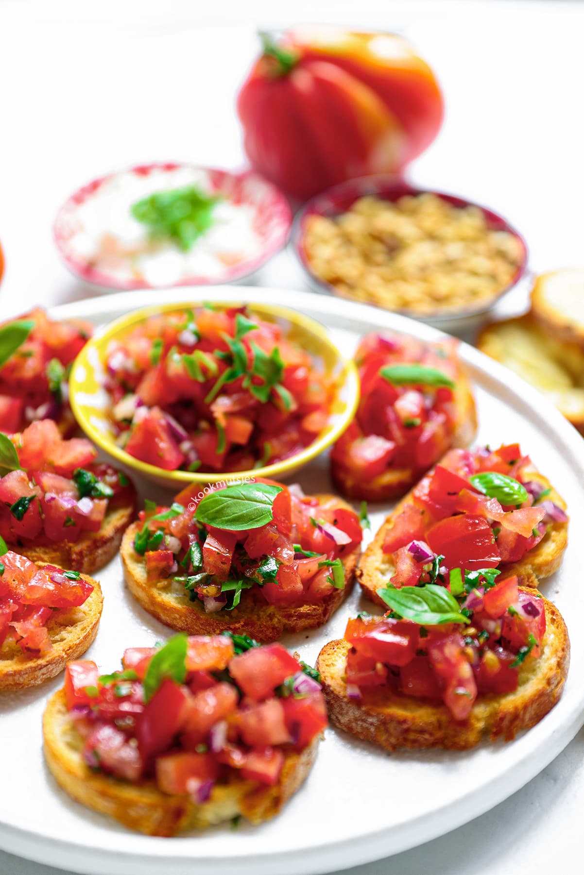 Tomatenmengsel wordt op krokant geroosterd brood geschept