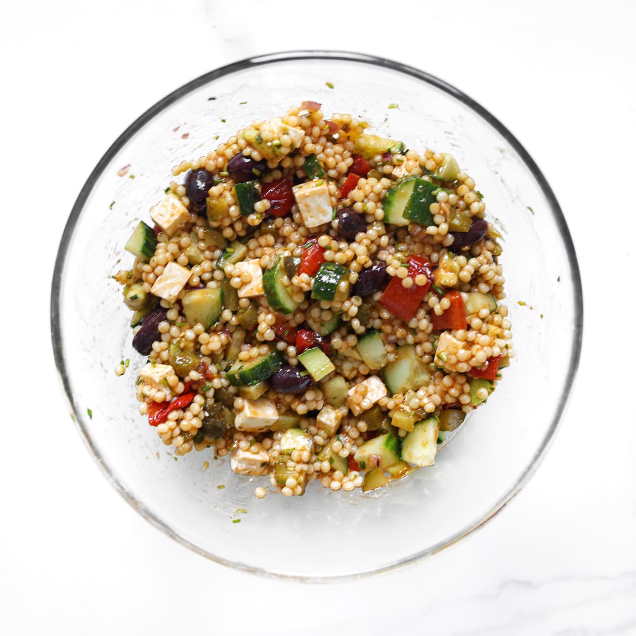 Zelfgemaakte parelcouscoussalade met feta, avocado, komkommer en olijven.