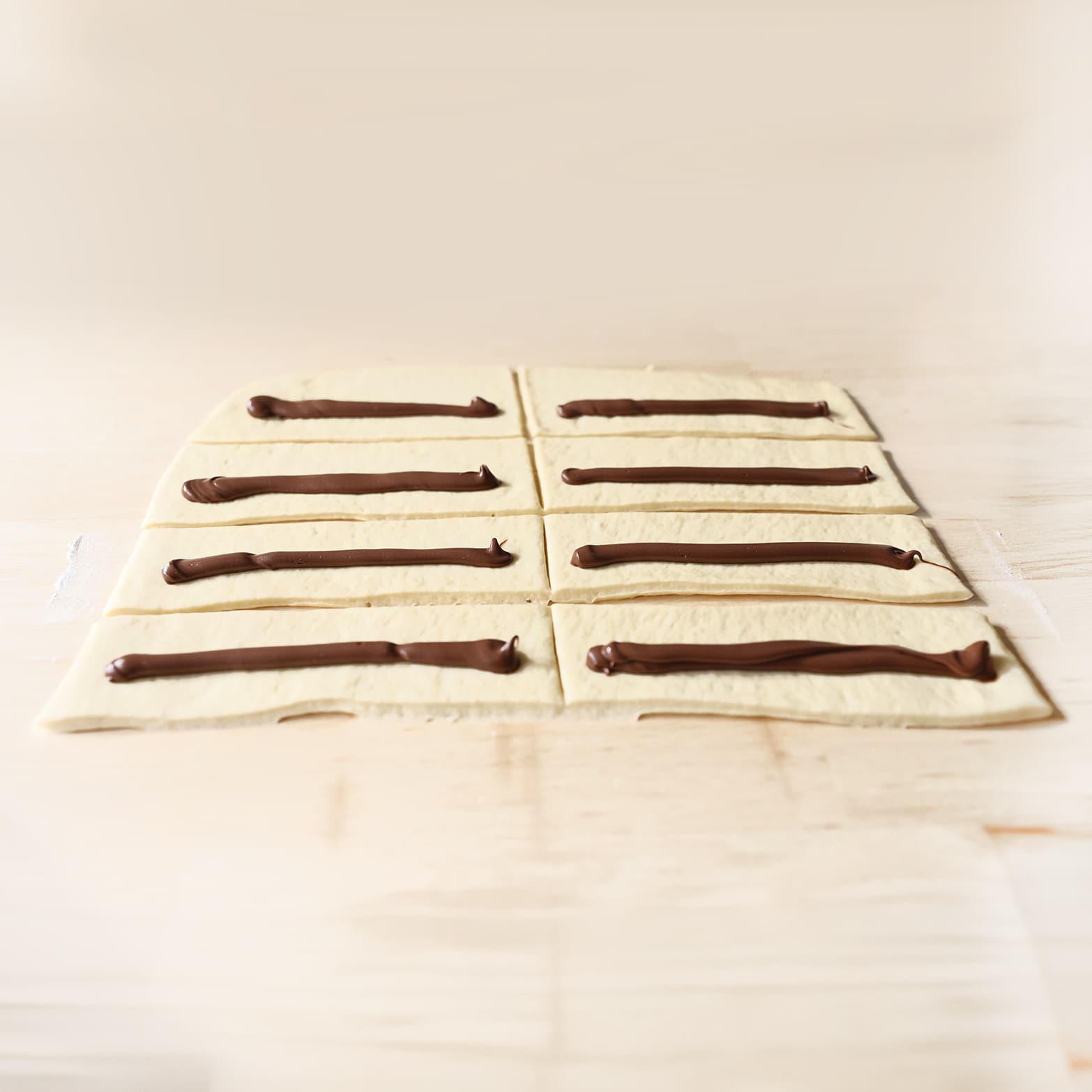 Chocoladepasta wordt op het deeg van een long donut gespoten