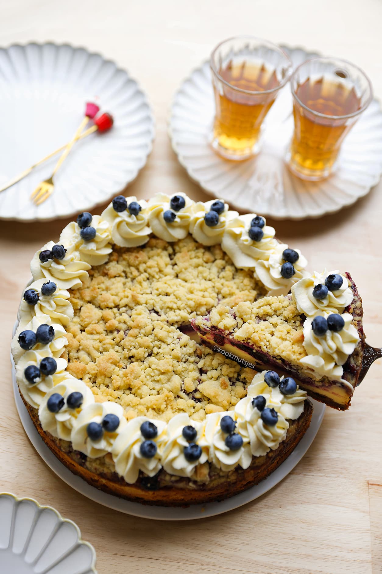 Aangesneden cheesecake met bosbessen, Biscoff-bodem en krokante koekkruimels
