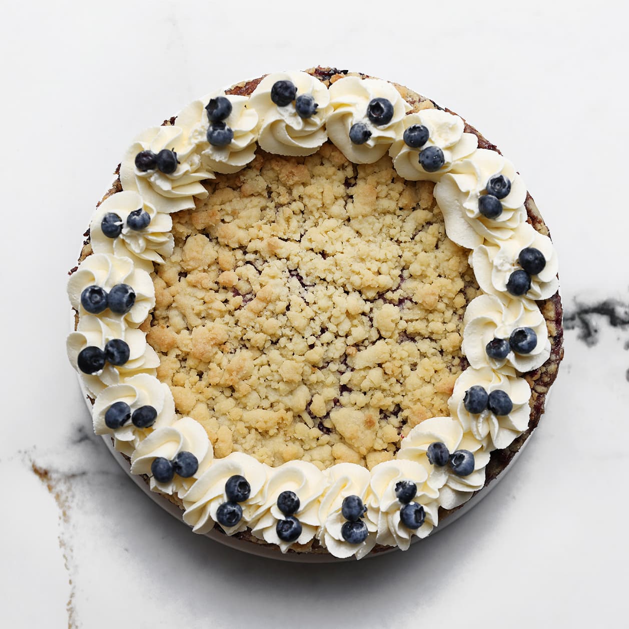 Cheesecake wordt afgewerkt met toefjes room en verse bosbessen
