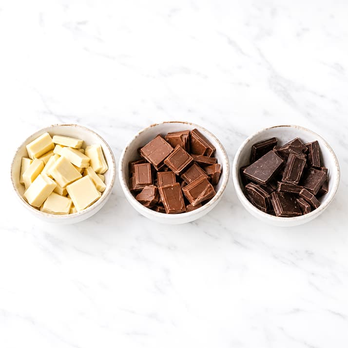 Melkchocolade, witte chocolade en pure chocolade in afzonderlijke blokjes breken.