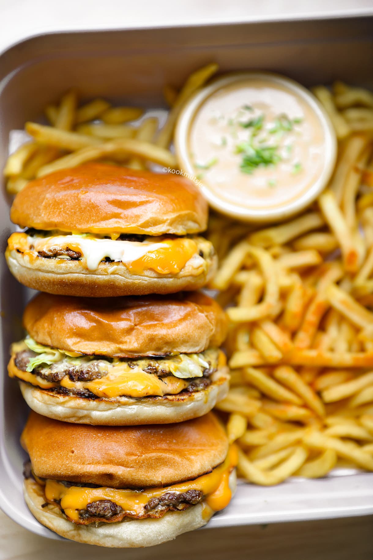 Double smashburger met gesmolten cheddar, augurk, ui en burgersaus