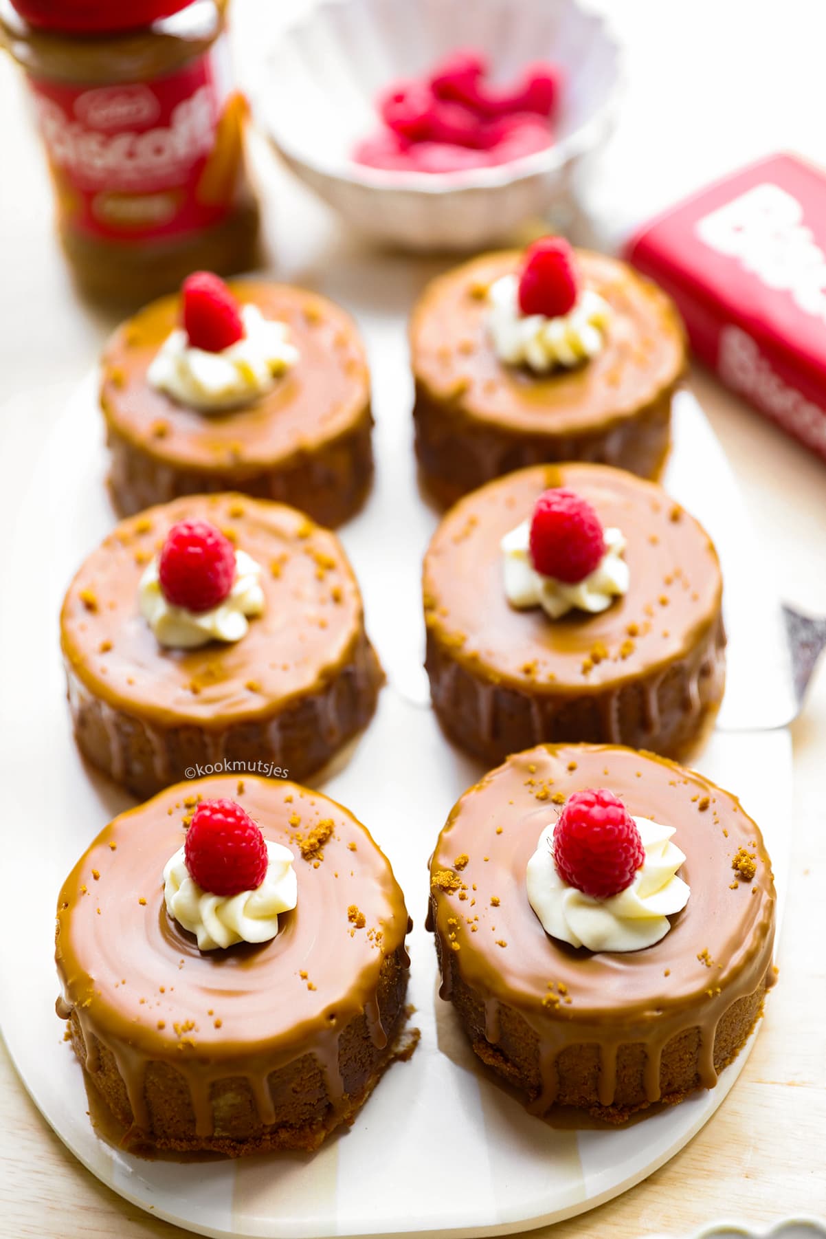 Close-up van een mini Biscoff-cheesecake met romige mascarponeroom, frambozen en krokante koekkruimels.