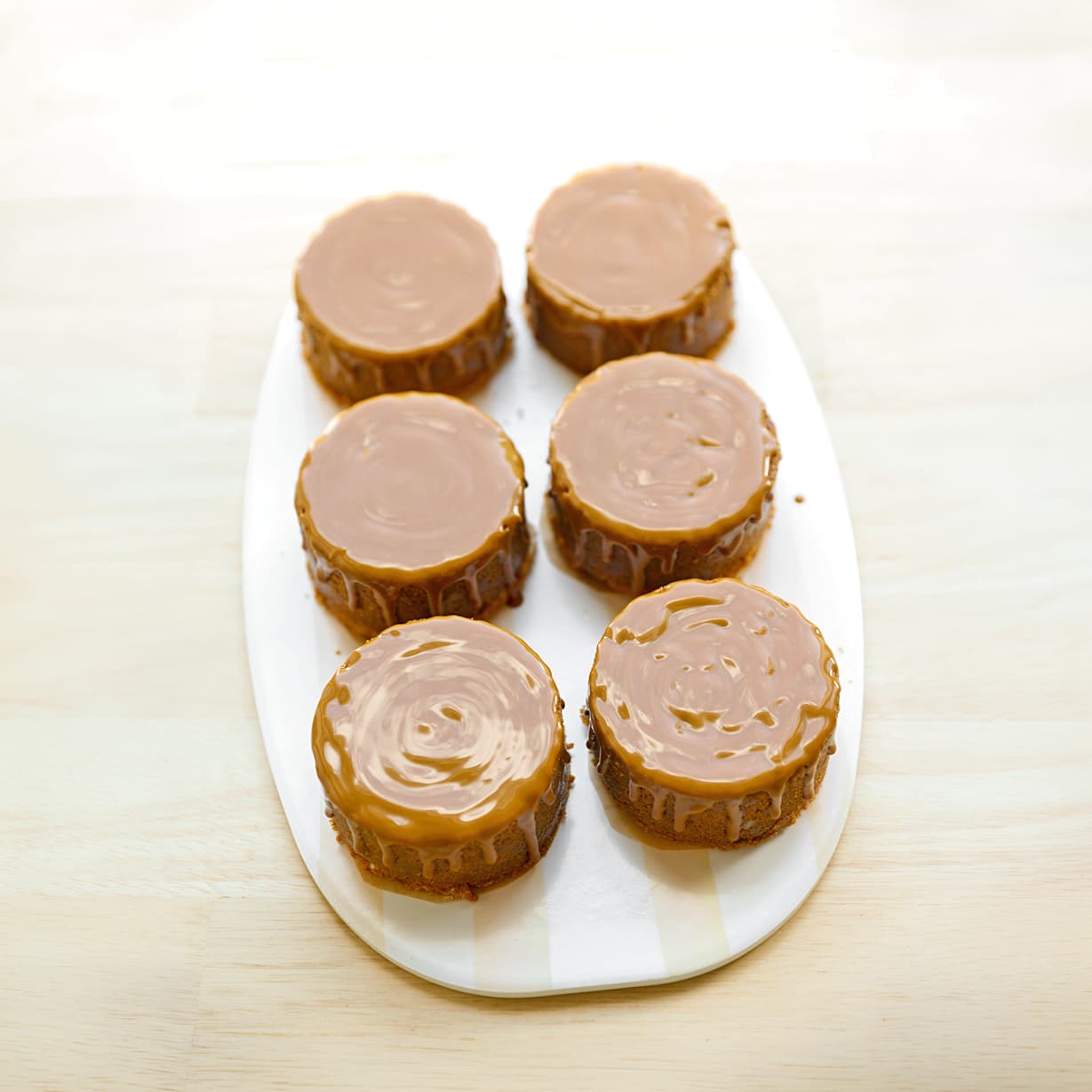 Vloeibare Biscoffpasta verdelen over de koekkruimellaag van mini upside down cheesecakes.