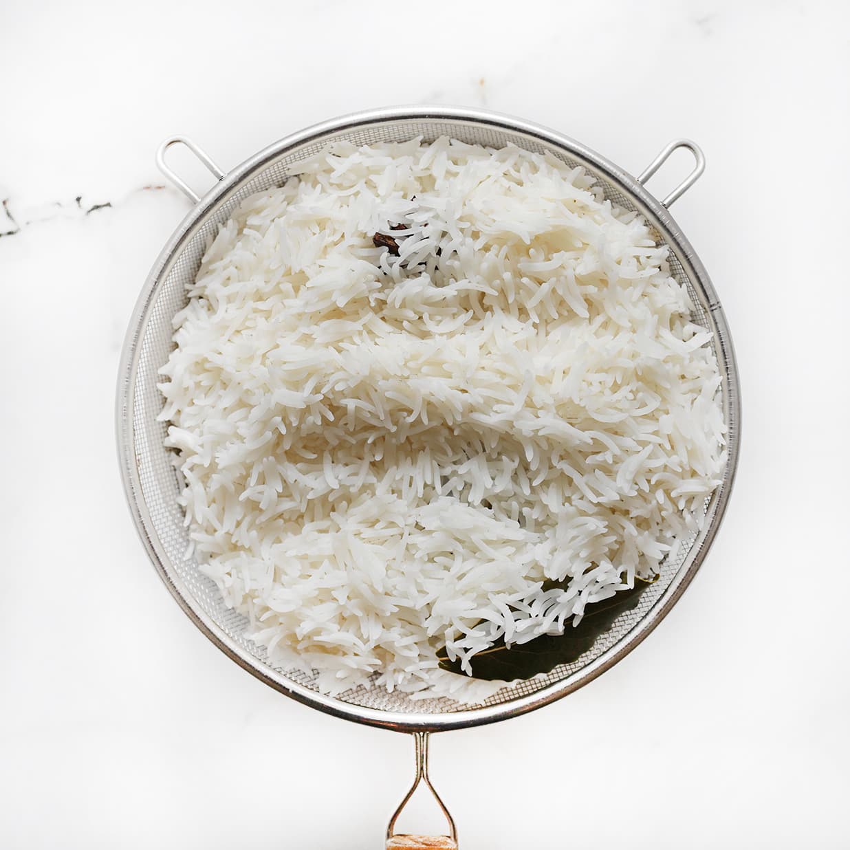 Geweekte basmatirijst in een zeef laten uitlekken voor kip biryani