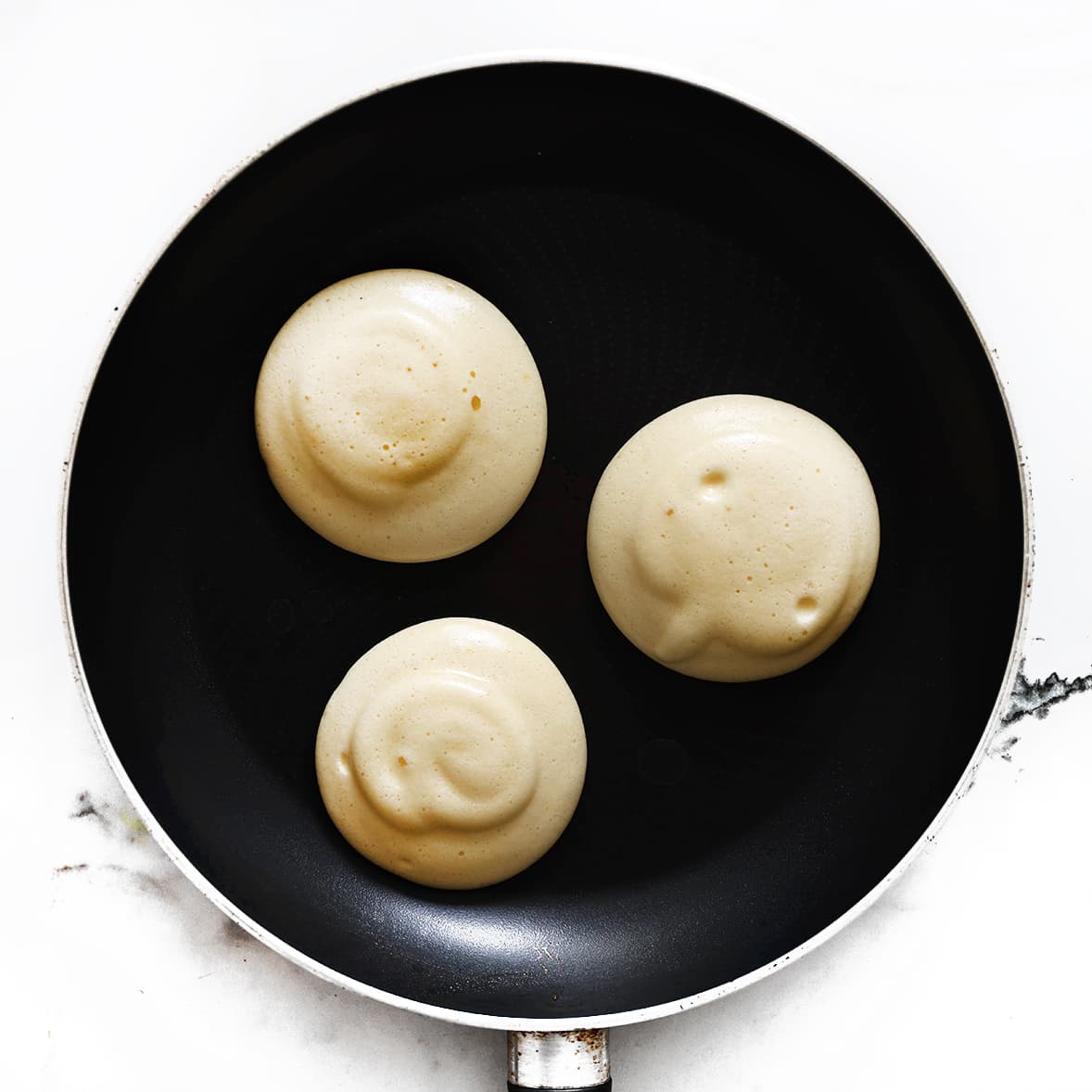 Beslag voor fluffy pancakes wordt in hoge hoopjes in een antiaanbakpan gespoten