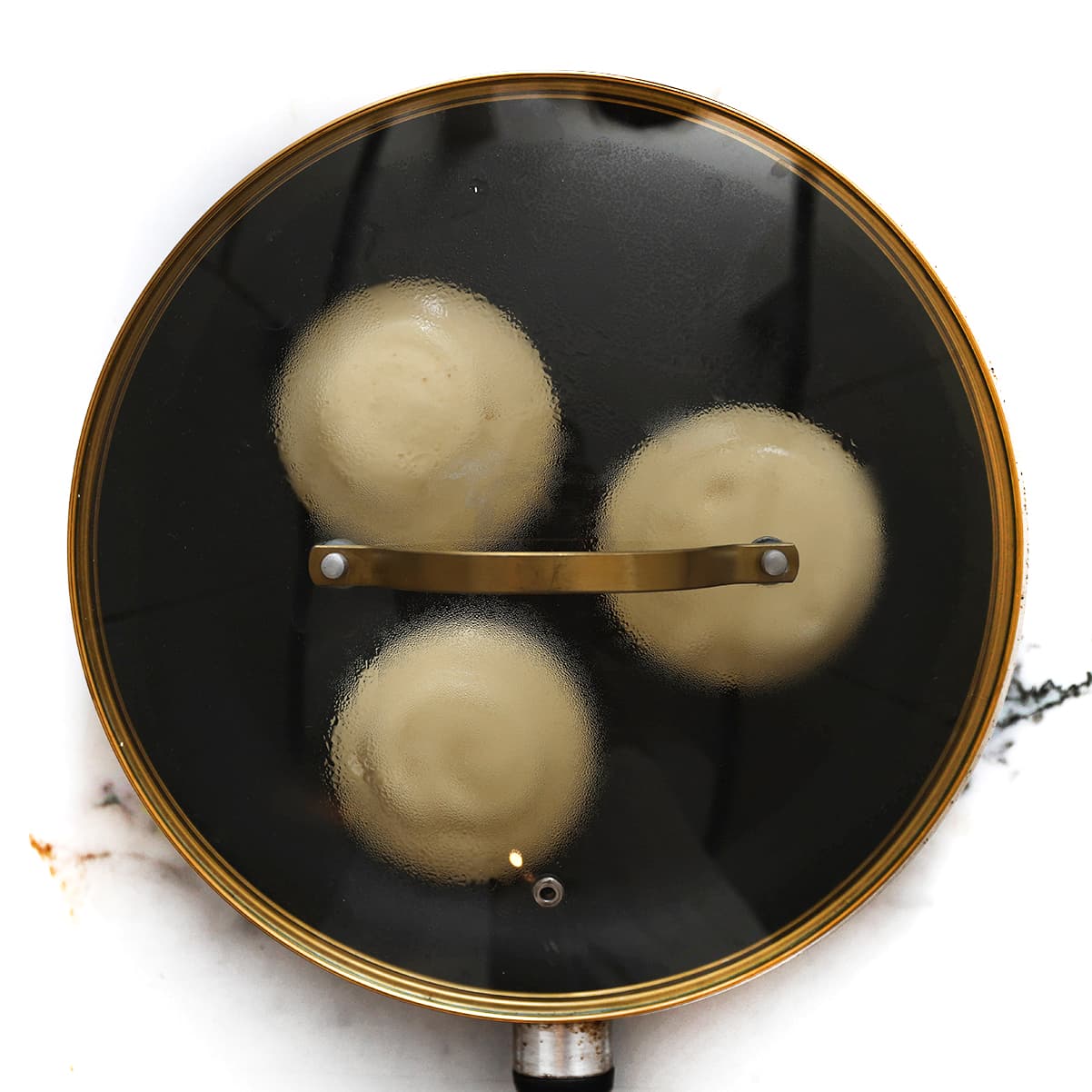 Hoge Japanse fluffy pancakes garen met deksel op de pan op laag vuur